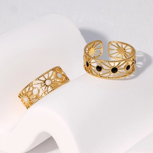 Detail view of gold geometric rings with sunburst hollow design and black white inlay