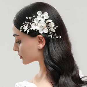 Elegant bridal hair clip with white shell flowers, pearls and crystals on dark hair