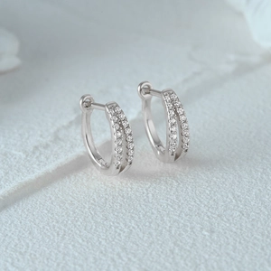Macro shot of silver S925 huggie earrings featuring double row of sparkling zircon stones