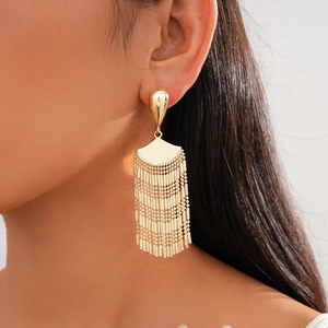 Close-up of golden fan-shaped fringe earrings worn by a model in a side-view shot