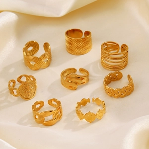 Set of eight gold geometric open rings displayed on elegant beige silk fabric texture