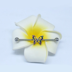 Close-up of a silver industrial barbell earring with a colorful crystal butterfly on a flower