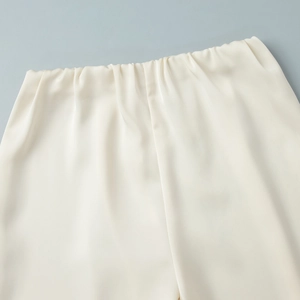 Detail showing elastic waist and soft satin texture of cream straight leg trousers