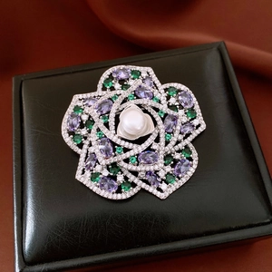 Macro shot of silver flower brooch with white pearl, zircons and purple gems on black box