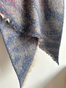 Détail d'une écharpe en cachemire synthétique à motif léopard bleu et rouge avec franges