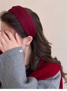 Close-up of a burgundy fabric headband and golden accessories on a female model