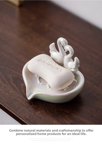Detail of elegant ceramic swan soap dish with pearlescent glaze on wooden surface