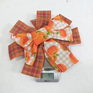 Detailed view of the layered pumpkin and plaid decorative bow weighing 47.1 grams