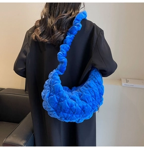 Detail of blue quilted velvet crescent bag showing texture and shoulder strap on model
