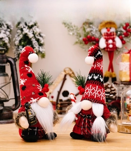 Close-up of knit Christmas gnomes with lantern and candy cane holiday decorations