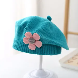 Detailed knit texture of a baby blue beret with a decorative pink crochet flower