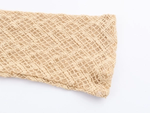 Detailed macro view of beige knit mesh fabric with intricate openwork lace patterns