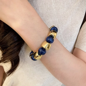 Close-up of luxury beaded bracelet with dark blue acrylic beads and gold metal spacers