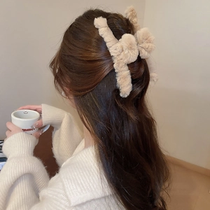 Detail of large beige plush hair claw clip styled on a woman's hair in winter