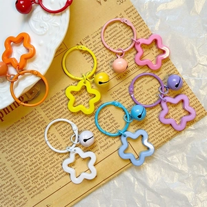 Colorful star-shaped acrylic keychains with matching bells on vintage newspaper background