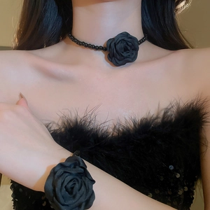 Détail du collier fleur en tissu noir et bracelet à perles portés par le mannequin