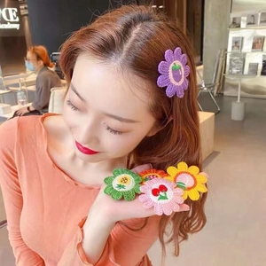 Detail of colorful knitted floral hair clips with embroidered cherry and strawberry motifs