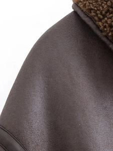 Detailed close-up of dark brown leather jacket with soft brown faux fur collar texture