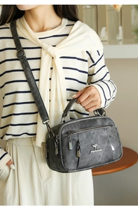 Close-up of a grey multi-pocket crossbody bag with soft faux leather texture on a model