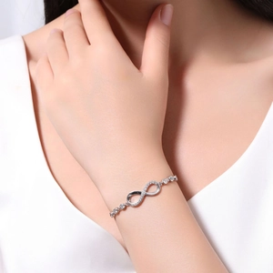Detailed view of silver infinity bracelet with clear zircons worn on a female wrist