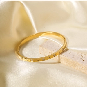 Dettaglio di un bracciale rigido placcato oro 18k con motivi a stella e zirconi su seta