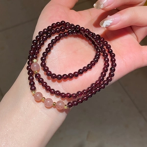 Close-up of triple-layer garnet and strawberry quartz beads with golden spacers on hand