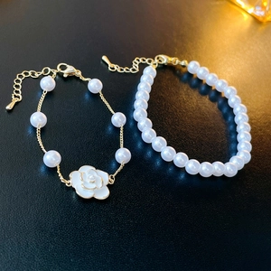 Detail of two-piece camellia faux pearl bracelets with gold plating and adjustable chains