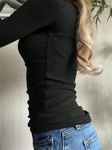 Slim fit black ribbed knit long sleeve top paired with blue jeans in a casual style