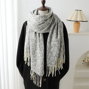 Detail of grey leopard print jacquard scarf with fringe draped on a mannequin