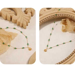 Detail of gold shell pendant necklace with green beads on a vintage textured surface