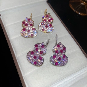 Detailed macro view of two pairs of Wulu-shaped earrings with red and white micro-set stones