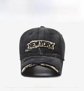 Detailed shot of New York embroidery and distressed ripped details on washed black denim cap