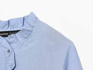 Detailed close-up of blue and white striped poplin shirt with ruffled collar detail