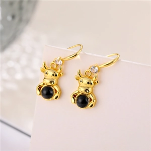 Creative golden ox earrings with black beads and crystal details in macro view