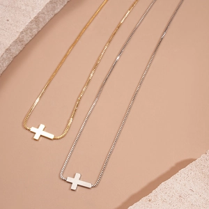 Minimalist 18k gold and silver plated cross pendant necklaces on warm background