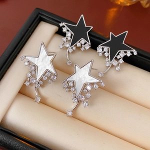 Macro view of black and white star earrings with diamond tassels in a jewelry box