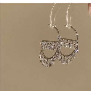 Macro detail of silver drop earrings with trapezoidal cubic zirconia on a stand