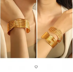 Detail of two gold-plated wide cuff bracelets with wave textures and woven designs