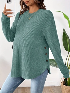 Detail of green ribbed knit maternity top with side button accents and long sleeves