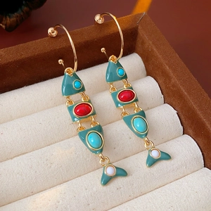 Macro detail of vintage jointed fish earrings with colorful enamel and gemstone accents