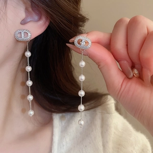 Detail view of silver tassel earrings with zircon studs and elegant pearls on model