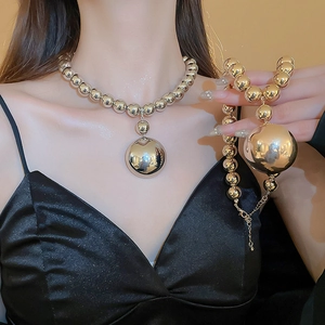 Polished gold metal bead necklace with large spherical pendant for a bold statement look