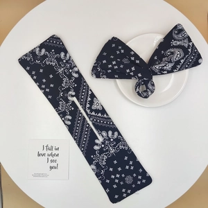 Detail of navy paisley bun hair tool and matching bow headband on a white table