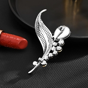 Silver leaf crystal brooch pin for women with detailed claw setting on a dark background