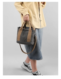 Detail of grey canvas tote bag with brown handles and adjustable crossbody strap
