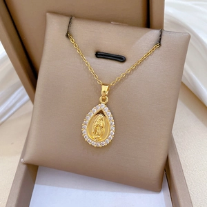 Macro shot of gold water-drop pendant with Virgin Mary relief and clear zircon inlay