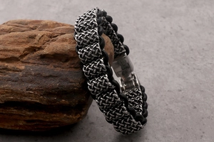 Close-up of men's braided leather bracelet with vintage basketweave stainless steel clasp