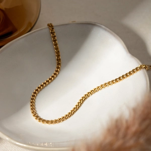 Classic 18K gold plated stainless steel 3mm Cuban link anklet on a white ceramic plate