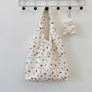 Detail of off-white crinkle fabric tote featuring cute cartoon dog patterns and stars