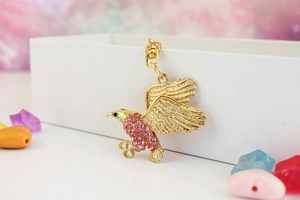 Detail eines goldenen Adler-Schlüsselanhängers mit rosa Strasssteinen am Keramikrand